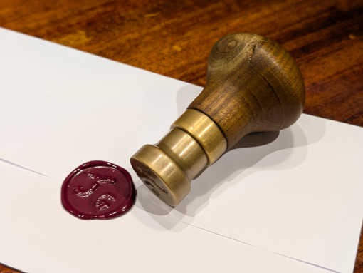 Prototype 1 of the wax seal stamp, next to a red seal on a small letter.